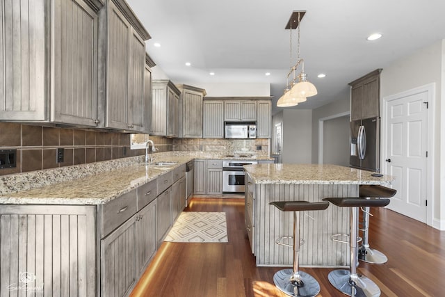 kitchen with stainless steel appliances, dark wood finished floors, a sink, and a kitchen island