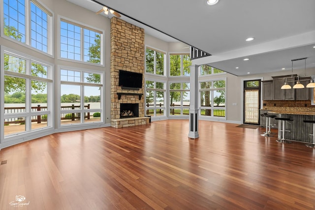 8043 Tamarack Ln, Morris, IL 60450 - unfurnished living room featuring wood finished floors, plenty of natural light, a stone fireplace, recessed lighting, and a towering ceiling