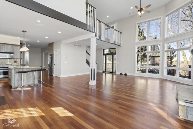 8043 Tamarack Ln, Morris, IL 60450 - unfurnished living room with ceiling fan, dark wood-style flooring, a towering ceiling, recessed lighting, and stairs