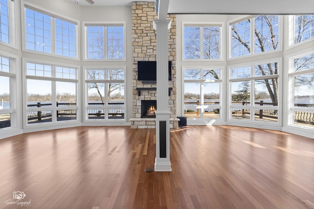 unfurnished living room featuring a high ceiling, a fireplace, and wood finished floors