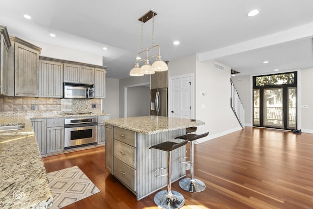 8043 Tamarack Ln, Morris, IL 60450 - kitchen with appliances with stainless steel finishes, dark wood finished floors, tasteful backsplash, light stone counters, and a kitchen breakfast bar