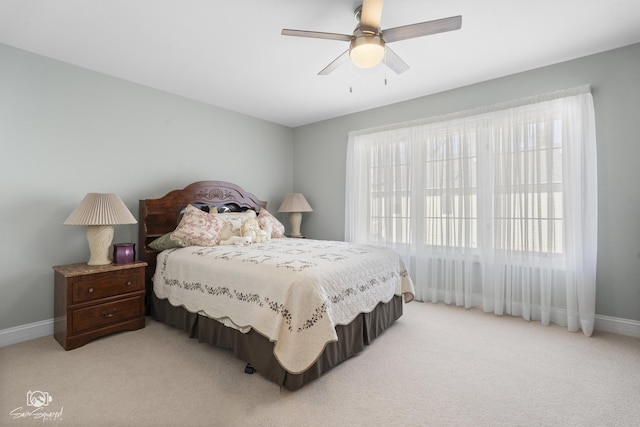 bedroom with multiple windows, light carpet, and baseboards