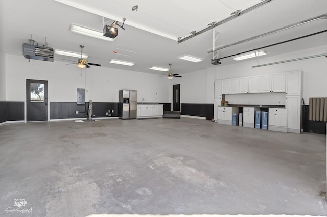 garage featuring electric panel, a garage door opener, a ceiling fan, and stainless steel fridge with ice dispenser