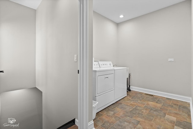 clothes washing area featuring stone finish floor, laundry area, baseboards, and washer and clothes dryer