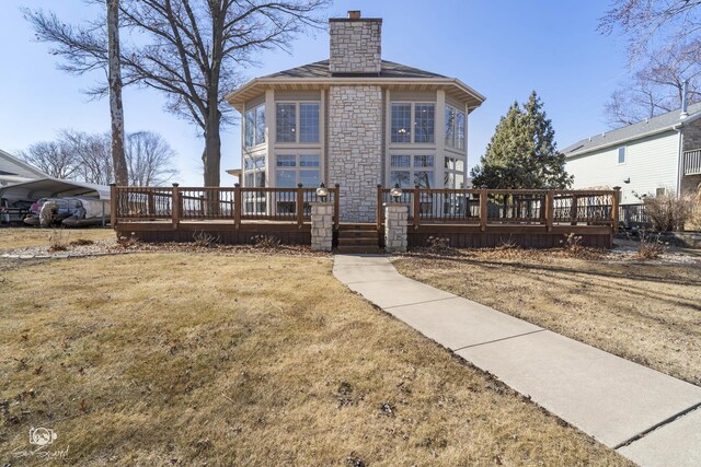 rear view of house featuring a yard, a chimney, and a wooden deck