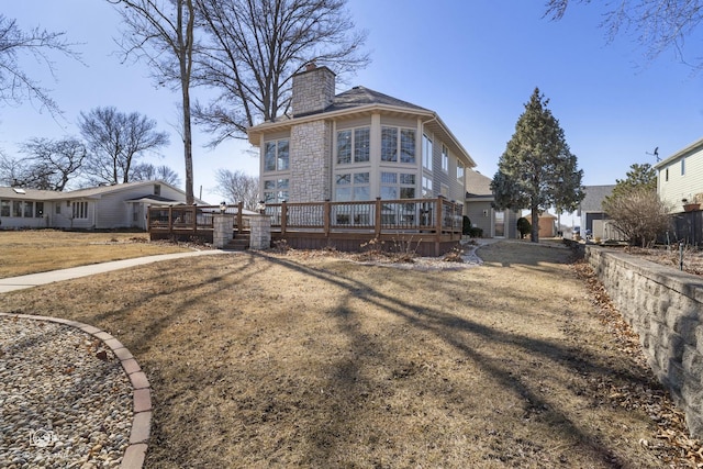 rear view of property with a yard, a chimney, and a wooden deck