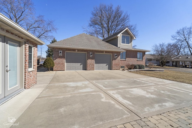 view of side of property featuring a shingled roof, brick siding, driveway, and an attached garage