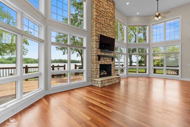 8043 Tamarack Ln, Morris, IL 60450 - unfurnished living room with a towering ceiling, plenty of natural light, a ceiling fan, a stone fireplace, and wood finished floors