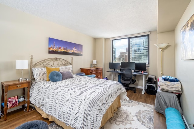 bedroom with baseboards, a textured ceiling, and wood finished floors