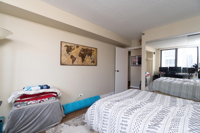 bedroom featuring wood finished floors, baseboards, and a textured ceiling