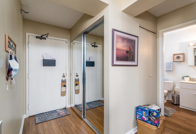 interior space with baseboards, a textured ceiling, and wood finished floors