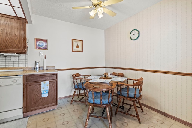 dining area with a textured ceiling, wallpapered walls, baseboards, and a ceiling fan