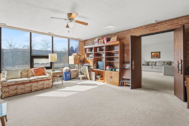 interior space featuring visible vents, brick wall, carpet flooring, a textured ceiling, and a ceiling fan