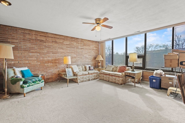 living area featuring visible vents, brick wall, and ceiling fan