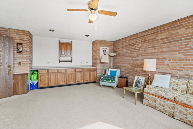 sitting room with ceiling fan, light carpet, and brick wall