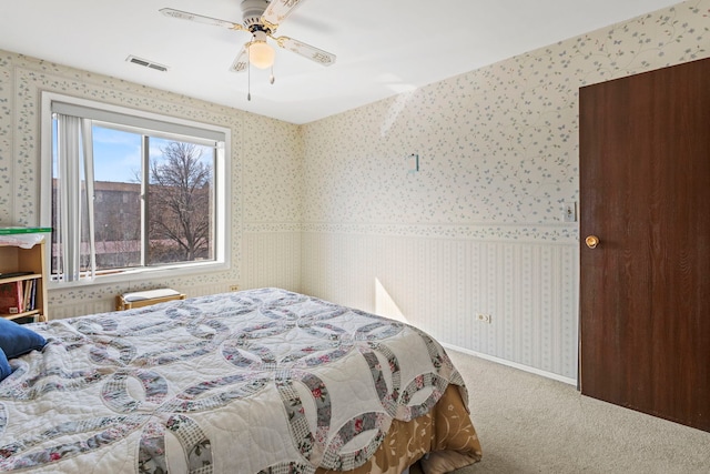 bedroom featuring visible vents, wallpapered walls, baseboards, carpet, and a ceiling fan