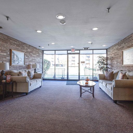 carpeted living room featuring brick wall and expansive windows