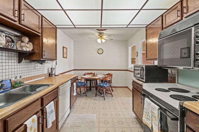 kitchen featuring stainless steel microwave, range with electric cooktop, a sink, and white dishwasher