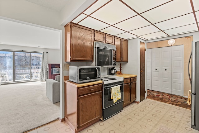 kitchen featuring open floor plan, light floors, light countertops, light carpet, and stainless steel appliances