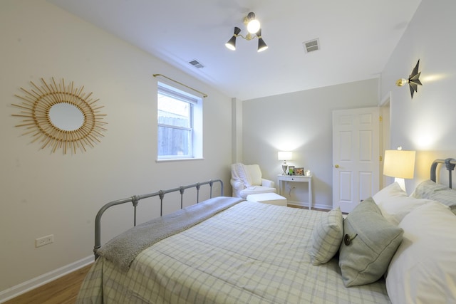 bedroom featuring visible vents, baseboards, and wood finished floors