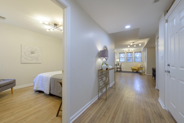 hallway with visible vents, baseboards, and light wood-style flooring