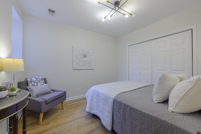 bedroom with visible vents, a notable chandelier, light wood-style flooring, a closet, and baseboards