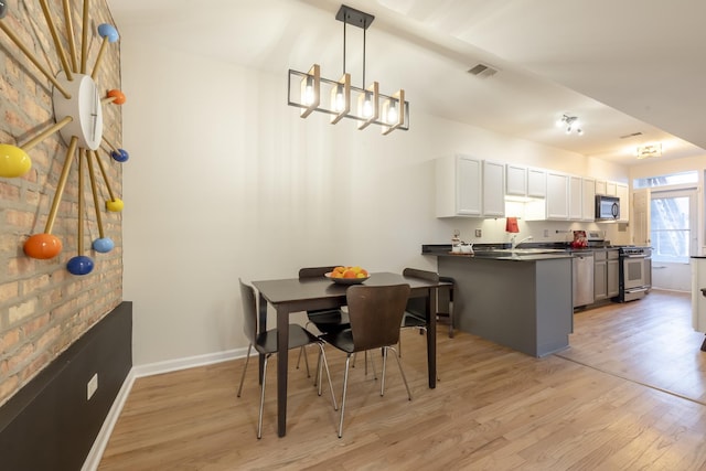 dining room featuring visible vents, baseboards, light wood-style flooring, and a chandelier