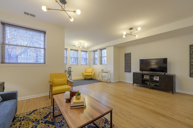 living area featuring an inviting chandelier, baseboards, visible vents, and light wood-type flooring