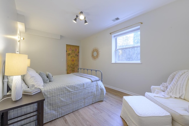 bedroom featuring visible vents, baseboards, and wood finished floors