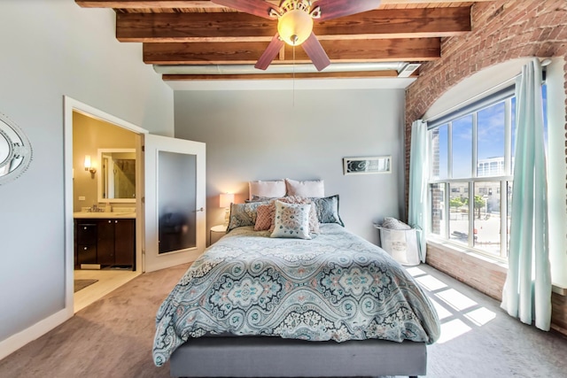 bedroom with brick wall, carpet floors, ensuite bath, ceiling fan, and beamed ceiling