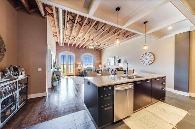 kitchen with a center island with sink, baseboards, dishwasher, and open floor plan