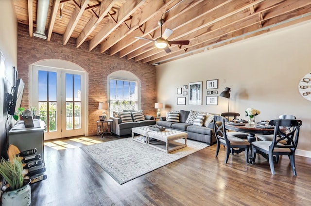 living room featuring brick wall, beamed ceiling, wood ceiling, wood finished floors, and a ceiling fan