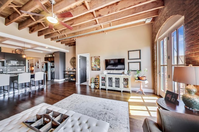 living area featuring beamed ceiling, wood finished floors, baseboards, wood ceiling, and ceiling fan