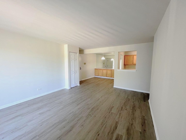 unfurnished living room with baseboards and wood finished floors