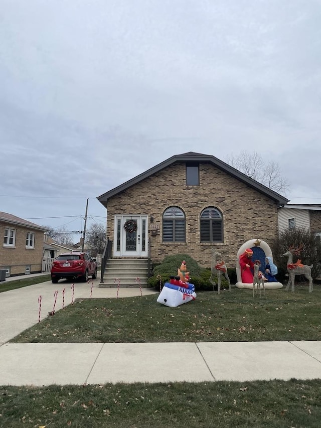 view of front of house with entry steps, a front lawn, and brick siding