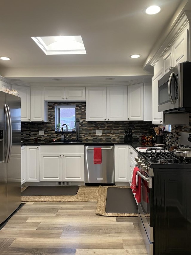 kitchen featuring a sink, dark countertops, appliances with stainless steel finishes, and white cabinets