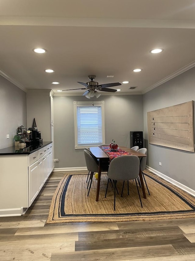 dining space with dark wood-type flooring, a ceiling fan, recessed lighting, crown molding, and baseboards