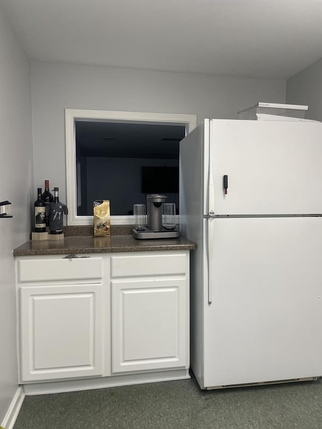 interior space featuring dark countertops, white cabinets, and freestanding refrigerator