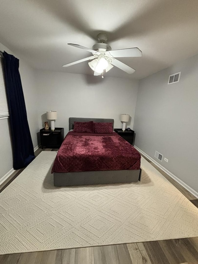 bedroom featuring ceiling fan, wood finished floors, visible vents, and baseboards