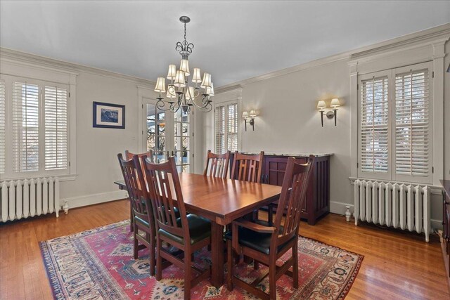 dining area with crown molding, radiator heating unit, wood finished floors, and a wealth of natural light