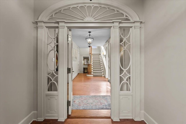 entrance foyer with baseboards, a notable chandelier, wood finished floors, and stairs