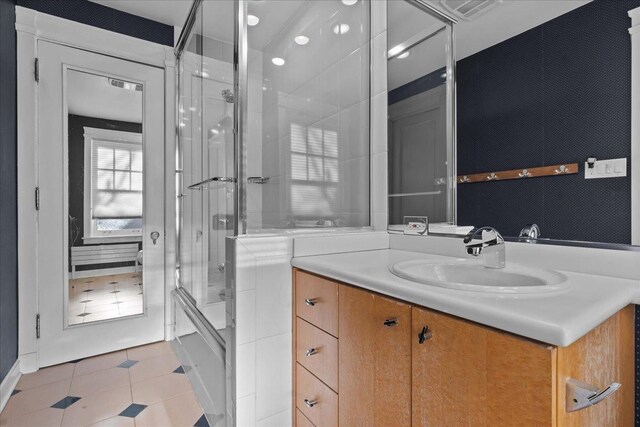 bathroom featuring tile patterned floors, vanity, and enclosed tub / shower combo