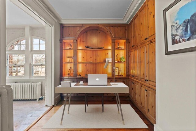 office featuring light wood-type flooring, radiator, and ornamental molding