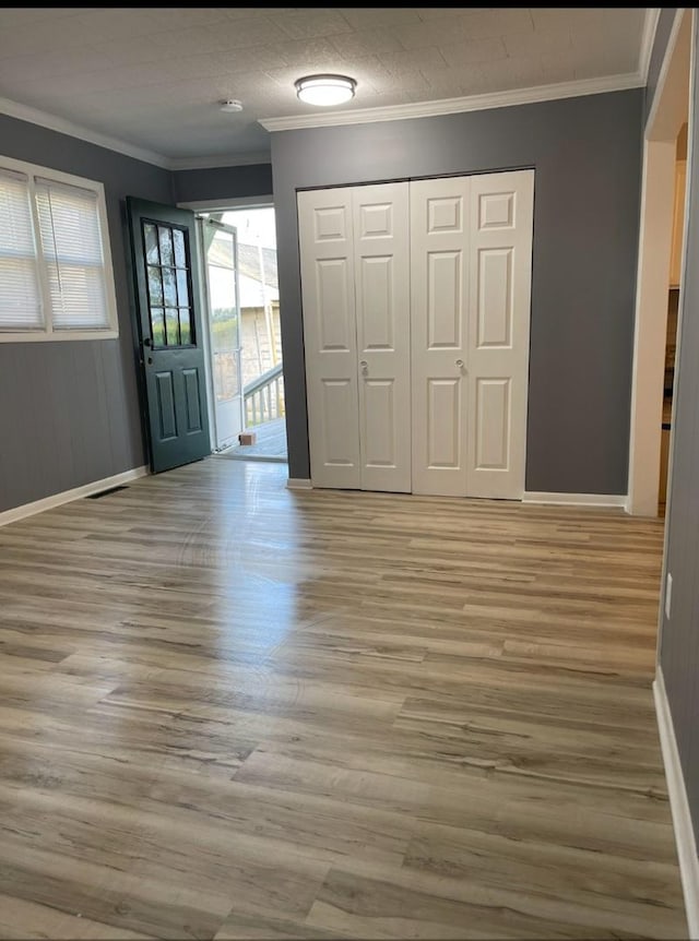 foyer entrance with light wood finished floors, crown molding, and baseboards