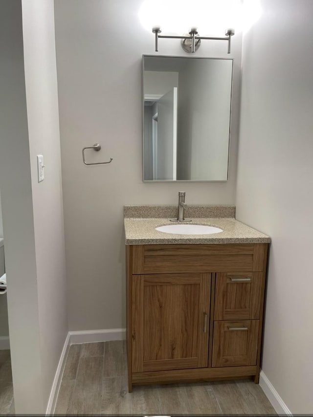 bathroom with vanity, baseboards, and wood finished floors