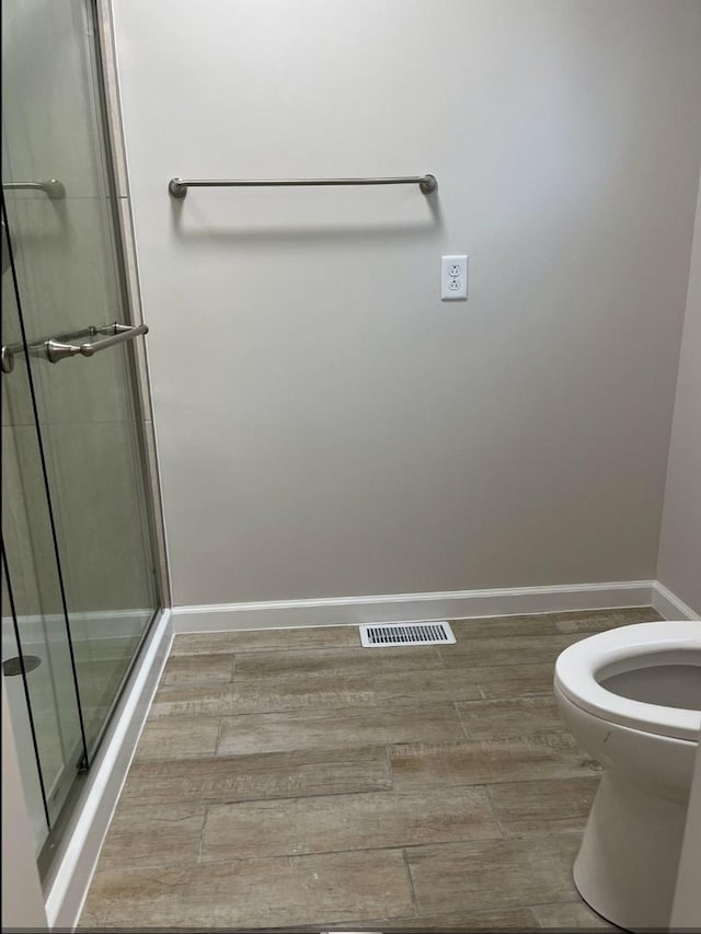 full bathroom with visible vents, a shower stall, baseboards, toilet, and wood finished floors