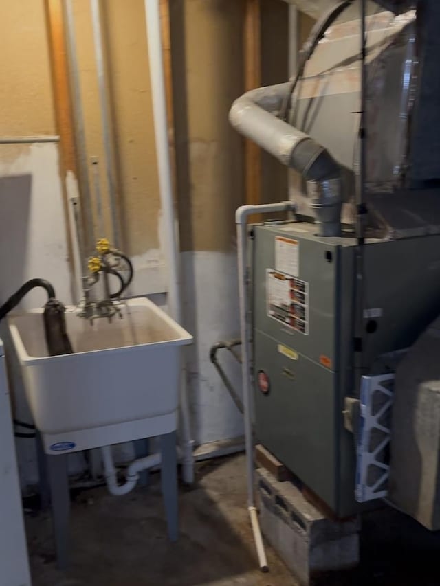 utility room with heating unit and a sink