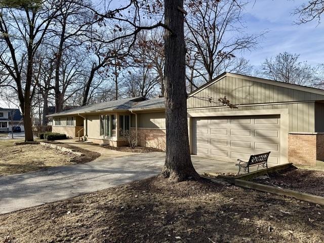 ranch-style house featuring brick siding, an attached garage, and driveway