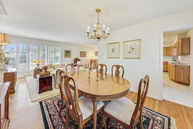 dining space featuring a notable chandelier, baseboards, and light wood-type flooring