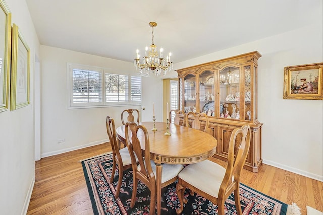 dining space featuring an inviting chandelier, baseboards, and light wood-style floors